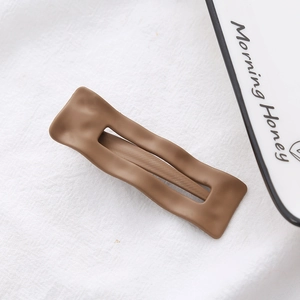 Close-up of matte brown rectangular hair clip with wavy texture and hollow center
