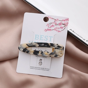 Detail of a geometric marble pattern hair clip on a floral display card with pink velvet