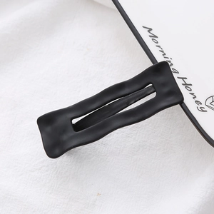 Detail of matte black wavy hair clip with frosted texture finish and metal structure