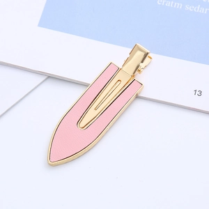 Elegant pink leather hair clip with golden metal base on a minimalist aesthetic background