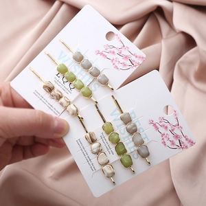 Detailed view of three resin marble texture hair clips with golden alloy base on pink silk