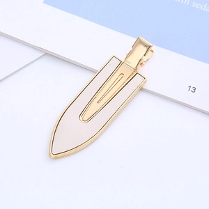 Detailed close-up of golden metal hair clip with elegant cream leather leaf inlay