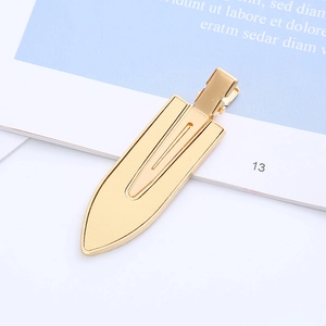 Detail of a golden metal hair clip with a smooth mirror finish on a minimalist background