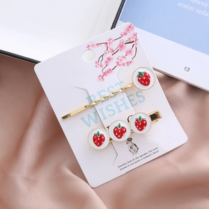 Set de barrettes à cheveux fraise dorées avec émail rouge sur carte de support