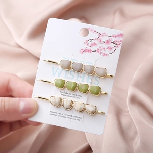 Three-piece gold hair clip set with faux natural stones on elegant floral card