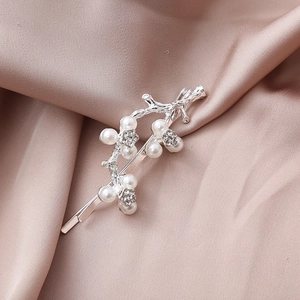 Detail of silver branch hair clip with white pearls and rhinestones on satin fabric