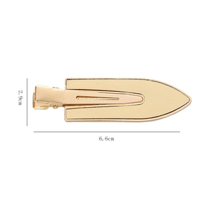 Macro detail of gold-tone minimalist hair clip with beige faux leather inlay, 6.6cm x 2.9cm