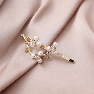 Detailed close-up of a golden branch hair clip with pearls and sparkling rhinestone flowers