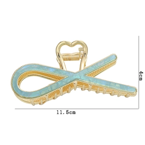 Detailed close-up of gold hair claw clip with mint green inlay and 11.5cm size markings
