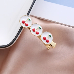 Vue détaillée de la pince à cheveux en émail motif cerise sur porcelaine blanche