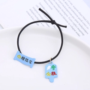 Detail of creative black elastic hair tie featuring blue exam blessing charms in a white dish
