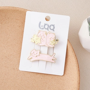 Detailed view of pink and gold cat-shaped alloy hair clips on a white display card