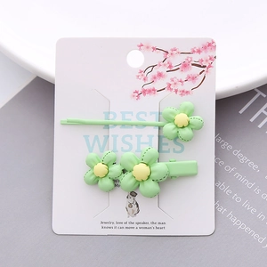 Set of two minimalist light green floral hair clips on a decorative card display