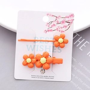 Detail view of orange floral hair clips with matte texture on decorative packaging card