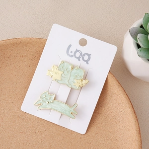 Detail view of two light green cat and star hair clips on a decorative ceramic tray