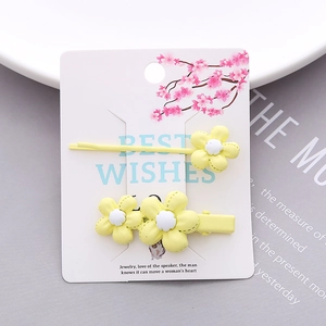 Set of two yellow floral hair clips on a decorative card, including a duckbill and side clip
