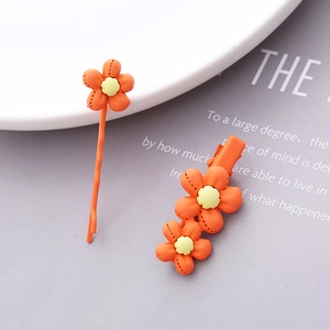 Detail of orange floral resin hair clip set featuring bobby pin and petal textures