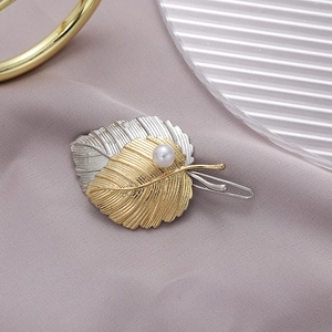 Elegant gold and silver leaf hair clip with white pearl on soft purple fabric