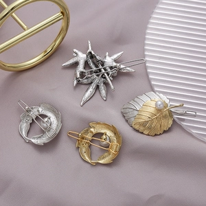 Macro detail of elegant gold and silver leaf hair clips with pearls on purple satin silk