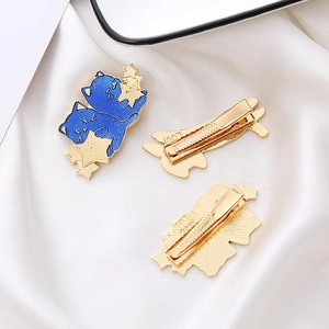Detail of blue cat hair clips with golden stars showing front and back metal duckbill clip