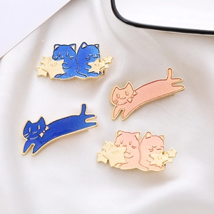 Detailed macro view of enamel cat brooches with glitter stars on white silk fabric