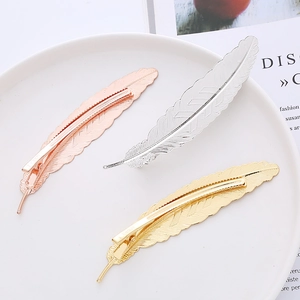 Three feather hair clips in gold, silver and rose gold finishes on a white plate
