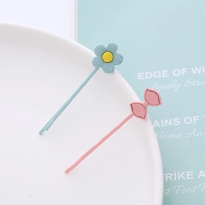 Détail de barrettes à cheveux macaron avec fleur bleue et nœud rose sur plat céramique