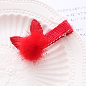 Detailed view of a red plush bunny ear hair clip with soft fur ball and metal base