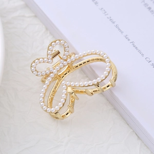 Detail shot of a butterfly hair claw clip with gold base and white pearl inlay