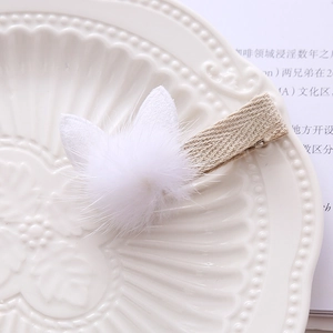 Detail of plush white bunny ear hair clip with beige fabric wrapped metal clip