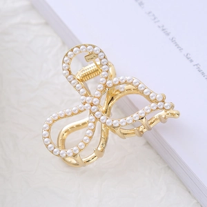 Detail of elegant gold metal hair claw with bow shape and white pearl embellishments