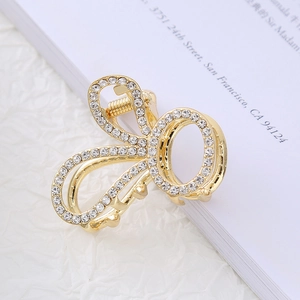 Close-up of golden hair claw clip with crystal rhinestones on a white book surface