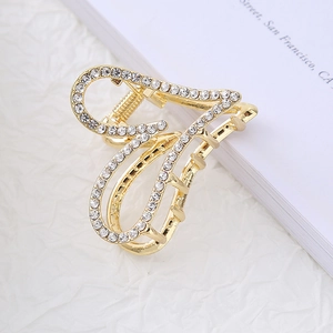 Close-up of golden heart-shaped hair claw clip with rhinestones and strong metal spring