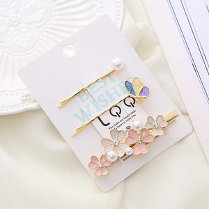 Three-piece floral and butterfly hair clip set with pink flowers and pearls on card