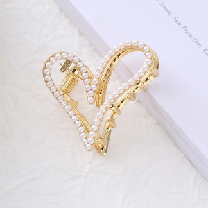 Detail view of heart-shaped gold alloy hair claw clip with inlaid white pearls