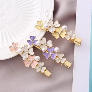 Detail of floral hair clips with enamel petals, pearls, and crystals on a gold base