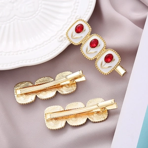 Detailed view of the gold-plated hair clips with white enamel and red crystal tulips