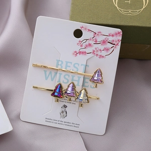 Elegant set of two crystal Christmas tree hair pins on a decorative display card