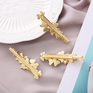 Detail of three golden floral hair clips with pearls on elegant purple satin background
