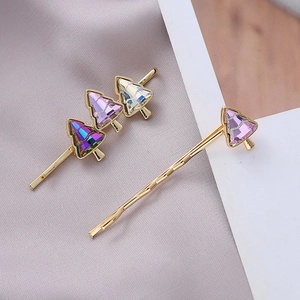 Detailed macro view of two gold hair clips with colorful crystal Christmas trees