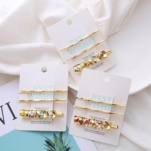 Three-piece gold metal hair clip set with multicolored crystals on a white display card