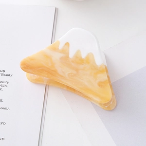 Detailed close-up of mountain shaped acetate hair claw with white top and orange marbling