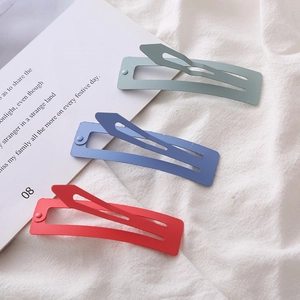 Close-up of matte rectangular metal BB hair clips in green, blue, and red colors