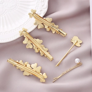 Close-up of golden hair clip set with hearts and pearls on purple silk fabric background