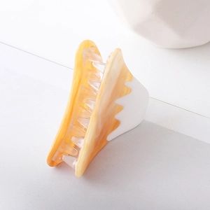 Macro view of a medium hair claw clip with amber marble texture and white resin splicing