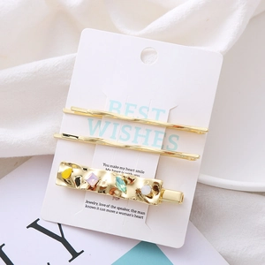 Three-piece set of golden hair clips with colorful crystals on a display card