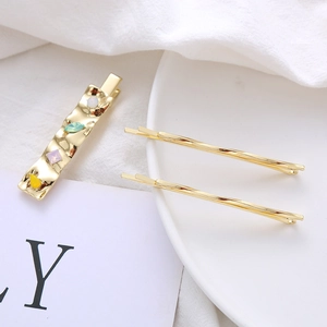 Detail of gold duckbill hair clip set with colorful crystals on a white ceramic plate