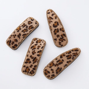 Detail of leopard print hair clips with velvet texture and golden rhinestone edges