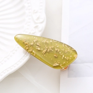 Macro detail of translucent olive green resin hair clip with embedded gold foil flakes