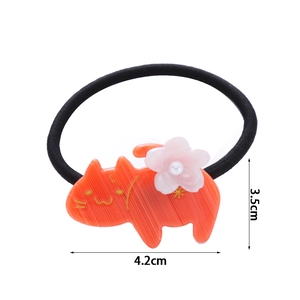 Dettaglio dell'elastico per capelli gatto in acetato arancione con fiore e perla bianca